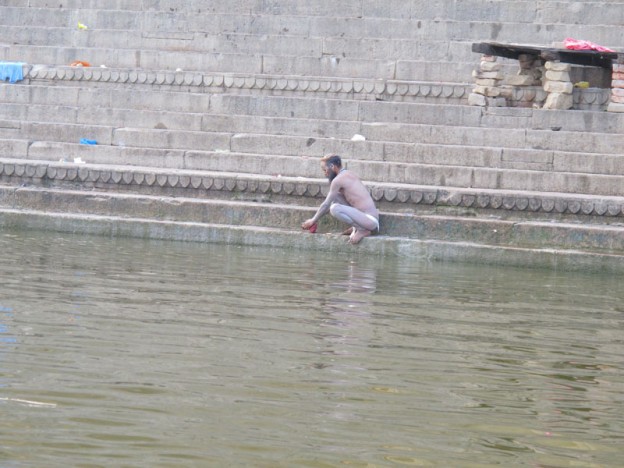 Man Washing Clothes at the Ghats Along the Ganges in Varanasi, India